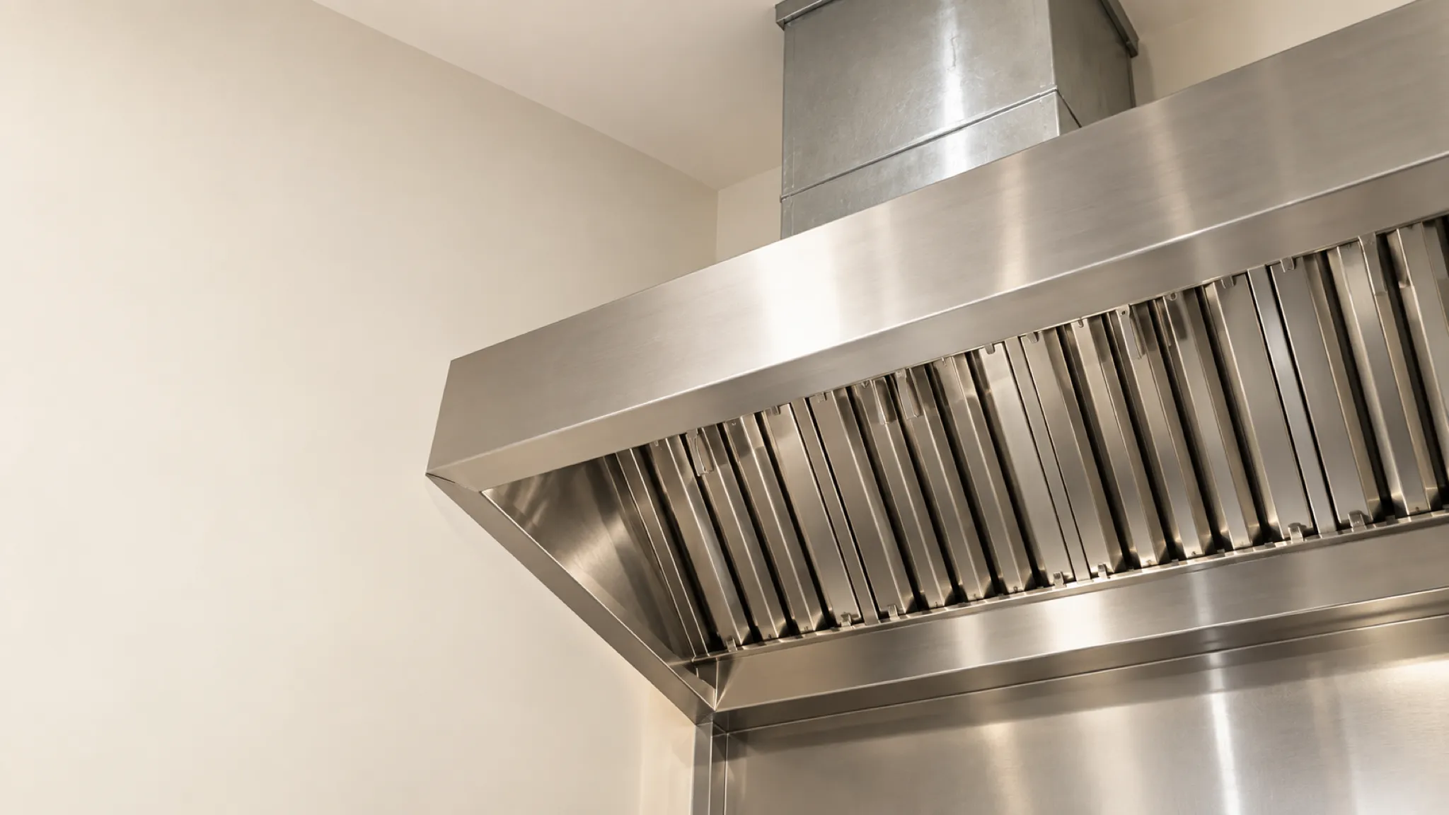 Looking up into a stainless exhaust hood: a row of baffle filters with the duct collar rising above them