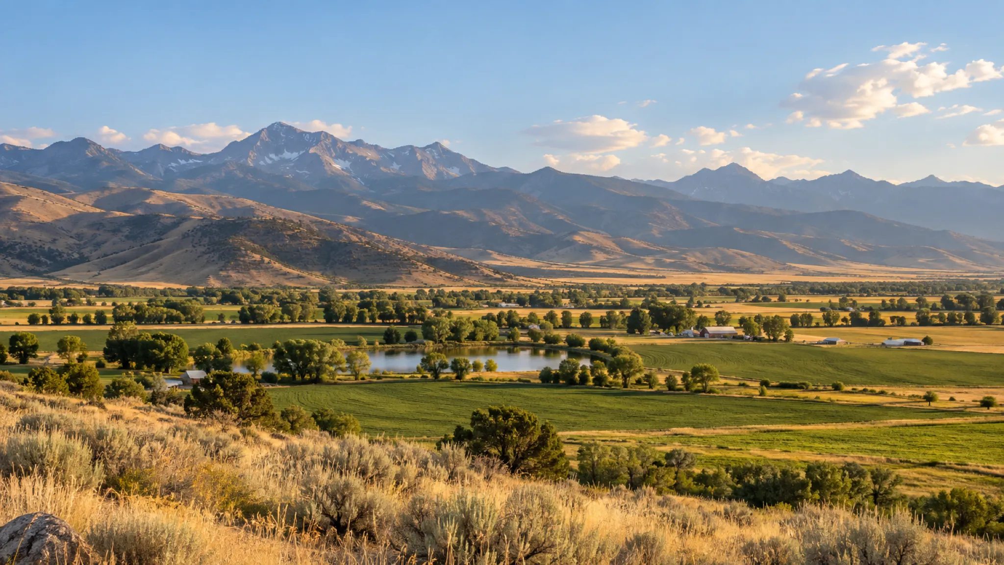 A wide high valley of farmland below dry foothills and a mountain range, typical of northern Utah and southern Idaho